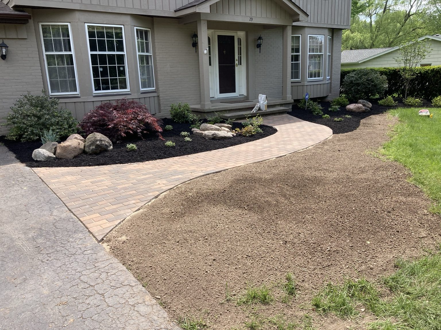 Curved paver walkway beside a landscaped home